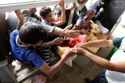 FILE - People crowd to get food rations from a charity kitchen in Sana'a, Yemen, July 20, 2020.