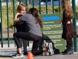 Una mujer hace una prueba de COVID-19 en la mejilla a un niño en un sitio de pruebas en North Hollywood, Los Angeles, el sábado 5 de diciembre de 2020, después que el gobernador ordenara estrictas restricciones por el aumento de casos de coronavirus.