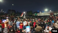 Massa aksi yang menolak omnibus law Cipta Kerja bertahan hingga malam hari di Depan Gedung DPR, Jakarta, Kamis (16/7/2020). (VOA/Sasmito)