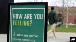 FILE - A sign at the University of Vermont reminds students to monitor their symptoms during the coronavirus pandemic, in Burlington, Vermont, April 27, 2021. 