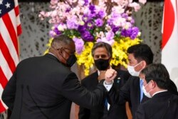 US Defense Secretary Lloyd Austin, left, elbow bumps with Japanese Defense Minister Nobuo Kishi as U.S. Secretary of State Antony Blinken, center, and Japan's Foreign Minister Toshimitsu Motegi, front, after a joint news conference, March 16, 2021.