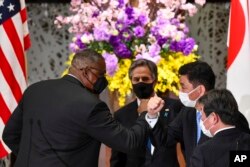 US Defense Secretary Lloyd Austin, left, elbow bumps with Japanese Defense Minister Nobuo Kishi as U.S. Secretary of State Antony Blinken, center, and Japan's Foreign Minister Toshimitsu Motegi, front, after a joint news conference, March 16, 2021.