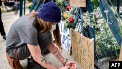 Una mujer enciende una vela durante una protesta frente a la embajada de los Estados Unidos en la Ciudad de México el 30 de mayo de 2020, en homenaje al estadounidense George Floyd.