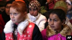 FILE - In this Wednesday, Jan. 27, 2016 file photo, Syrian refugee children sit on the ground as they listen to their teacher inside a tent, home for a refugee family that has been turned into a makeshift school, in a Syrian refugee camp in the eastern town of Kab Elias, Lebanon. 