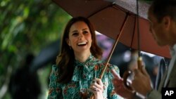 FILE - Britain's Prince William and his wife Kate, Duchess of Cambridge smile as they walk through the memorial garden in Kensington Palace, London, Aug. 30, 2017.