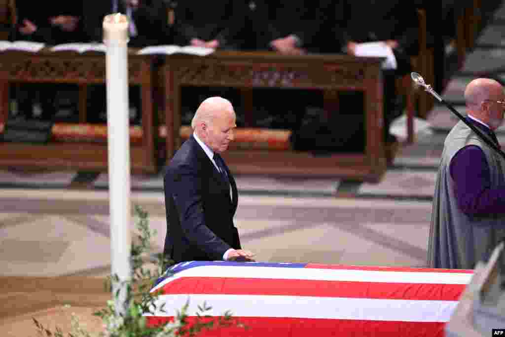 President Joe Biden touches the casket of former President Jimmy Carter as he makes his way to deliver a eulogy at the Washington National Cathedral, Jan. 9, 2025.