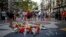 A woman places a flower around a memorial tribute of flowers, messages and candles on Barcelona's historic Las Ramblas in Barcelona, Aug. 16, 2018, the day before to the anniversary of the attacks that took place here on Aug. 17, 2017 killing 16 people and injuring more than 120. 