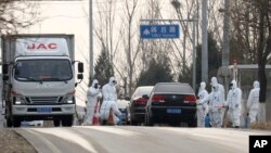 FILE - Workers disinfect passing vehicles in an area experiencing an African swine fever outbreak on the outskirts of Beijing, China, Nov. 23, 2018. 