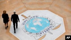 FILE - People walk past the Interpol logo at the headquarters of the international police agency in Lyon, France, Nov.8, 2018. 