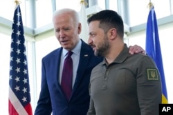 Presiden Joe Biden, kiri, berjalan bersama Presiden Ukraina Volodymyr Zelenskyy menjelang sesi kerja mengenai Ukraina pada KTT G7 di Hiroshima, Jepang, Minggu, 21 Mei 2023. (Foto: AP)