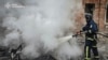 In this photo provided by the Ukrainian Emergency Services on Nov. 25, 2024, a rescue worker puts out a fire of a burned car in the yard of an apartment building damaged by a Russian strike on a residential neighborhood in Kharkiv, Ukraine. 