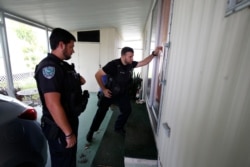 Vero Beach police officers James Doty and Chayse Hatfield, left, knock on doors to notify residents of a trailer park community of a mandatory evacuation, in preparation for Hurricane Dorian, in Vero Beach, Fla., Sept. 2, 2019.