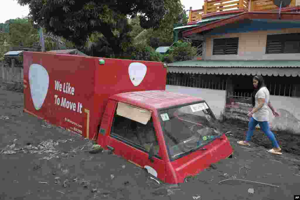 A nonmigratory  walks walk  a motortruck  buried by volcanic mud that flowed down   from Mayon volcano aft  dense  rains caused by Tropical Storm Trami deed  Guinobatan town, Albay province, Philippines.