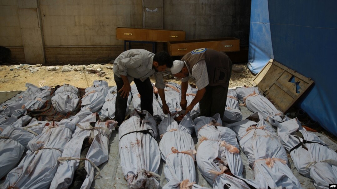 Petugas darurat Suriah dan seorang warga sipil memeriksa mayat warga Suriah yang dibungkus plastik di luar rumah sakit darurat di kawasan yang dikuasai pemberontak di Douma, bagian timur ibukota Damaskus, setelah serangan udara yang dilakukan oleh pasukan pemerintah, 1 Agustus 2015. (Foto: dok.)