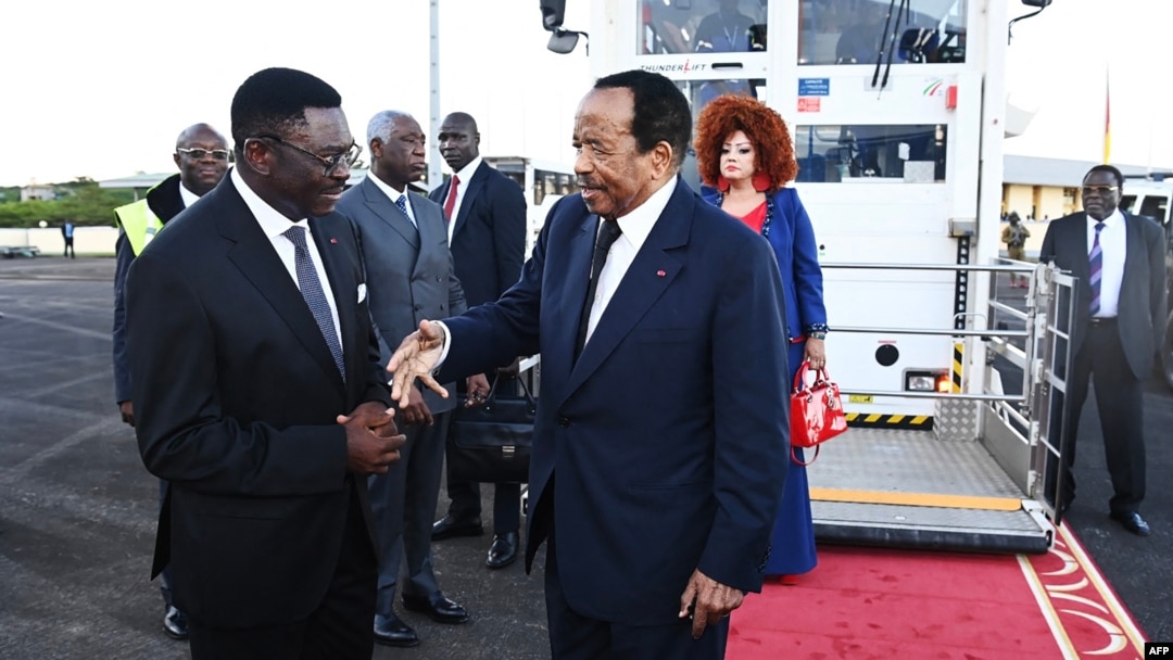 This handout picture taken and released on Oct. 21, 2024, by Cameroon's Presidential Press Office shows Cameroon's President Paul Biya, center, and his wife Chantal Biya (center-right) greeted upon their return, at the Yaounde Nsimalem International Airport. 