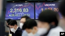 Currency traders watch computer monitors near the screens showing the Korea Composite Stock Price Index (KOSPI), left, and the foreign exchange rate between the US dollar and South Korean won in Seoul, South Korea, Oct. 29, 2020.