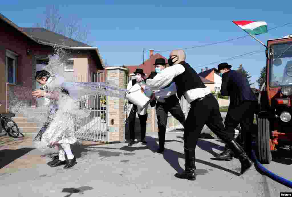 Members of the Hungarian dance and folk art ensemble Marcal throw water at a woman as part of traditional Easter celebrations in Gyor-Menfocsanak, Hungary.