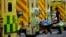 FILE - A patient is pushed on a trolley after arriving in an ambulance outside the Royal London Hospital in the Whitechapel area of east London, Thursday, Jan. 6, 2022. 