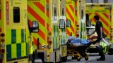 A patient is pushed on a trolley after arriving in an ambulance outside the Royal London Hospital in the Whitechapel area of east London, Thursday, Jan. 6, 2022. 