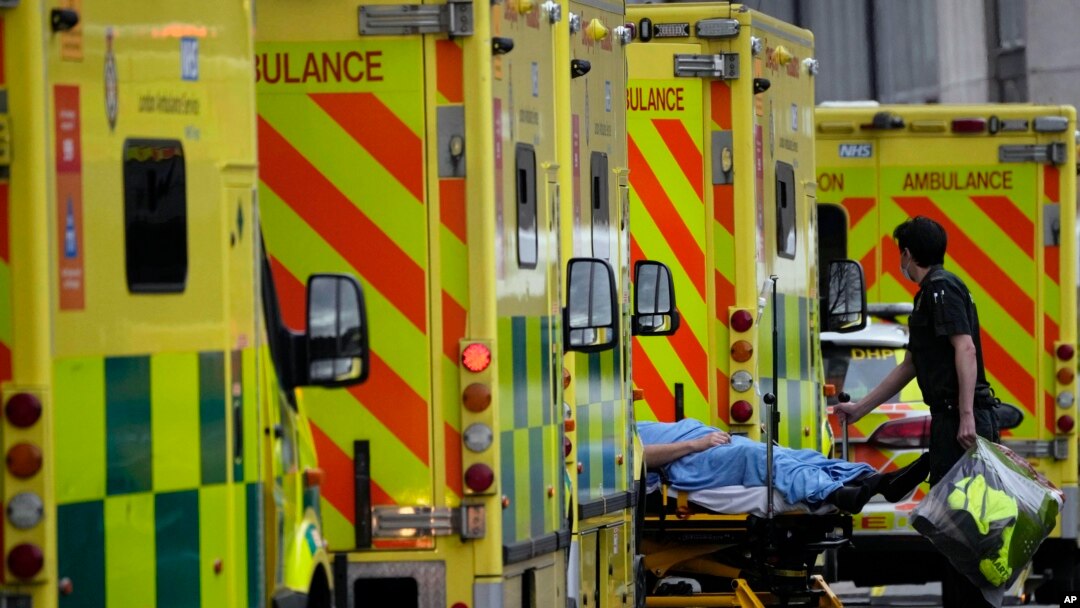 Seorang petugas menangani seorang pasien COVID-19 yang baru tiba dengan ambulans di sebuah rumah sakit di pinggiran London, Inggris (foto: dok). 