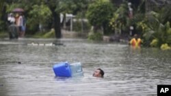 ຜູ້​ຊາຍ​ກໍາລັງ​ຜ່າ​ນໍ້າ​ຝົນ ທີ່​ສູງ​ພຽງ​ຄໍ ​ໃນ​ເມືອງ Quezon City ທາງທິດ​ເໜືອ​ຂອງກຸງ Manila, ຟີລິບປິນ, ວັນທີ 7 ສິງຫາ 2012.