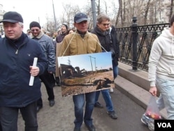 FILE – A protester holds a photo during a mass demonstration in Moscow against the Russian annexation of Crimea in 2014.