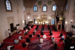Worshippers wearing masks to help stop the spread of the coronavirus offer Eid al-Adha prayer while maintaining a social distance at the Gazi Husrev-beg mosque in Sarajevo, Bosnia, Friday, July 31, 2020.