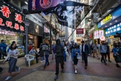 A pro-democracy protester waves a flag as protesters and office workers march past business shop lots during a protests at Causeway Bay in Hong Kong, Wednesday, Dec. 11, 2019.