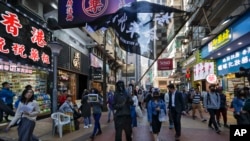 A pro-democracy protester waves a flag as protesters and office workers march past business shop lots during a protests at Causeway Bay in Hong Kong, Dec. 11, 2019. 