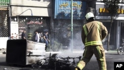 In this photo taken by an individual not employed by the Associated Press and obtained by the AP outside Iran, an Iranian fire fighter extinguishes a burned motorcycle in a street in central Tehran, near Tehran's old main bazaar, October 3, 2012. 