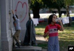 FILE - A girl drinks water in the transit center for refugees in Sid, about 100 km west from Belgrade, Serbia, Sept. 15, 2016.