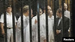 FILE - Ousted former Egyptian president Mohamed Mursi (R) speaks with other senior figures of the Muslim Brotherhood in a cage in a courthouse on the first day of his trial, in Cairo, Nov. 4, 2013. 