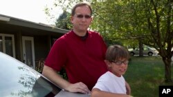 Lowell Highby and his adopted son, Alex, pose in front of their hom in Iowa, Jul. 10, 2012.