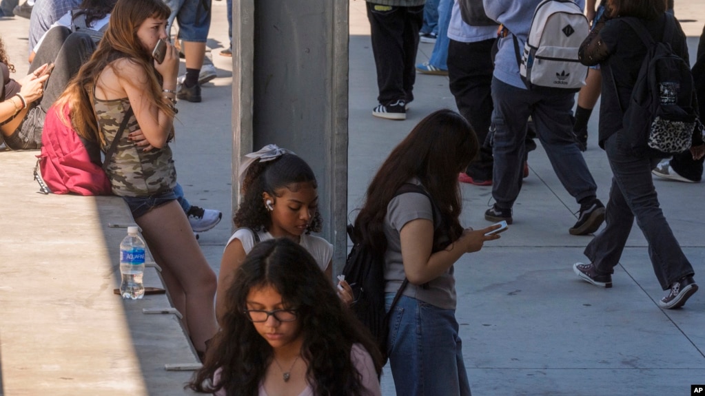 In this file photo, students use their cellphones as they leave for the day the Ramon C. Cortines School of Visual and Performing Arts High School in downtown Los Angeles, Aug. 13, 2024. (AP Photo/Damian Dovarganes, File)