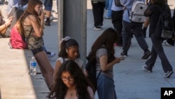 In this file photo, students use their cellphones as they leave for the day the Ramon C. Cortines School of Visual and Performing Arts High School in downtown Los Angeles, Aug. 13, 2024. (AP Photo/Damian Dovarganes, File)