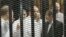 FILE - Ousted former Egyptian president Mohamed Mursi (R) speaks with other senior figures of the Muslim Brotherhood in a cage in a courthouse on the first day of his trial, in Cairo, Nov. 4, 2013. 