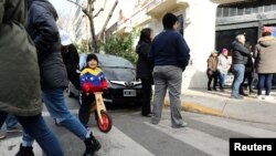 Un niño vistiendo los colores de la bandera venezolana juega en una calle de Buenos Aires.