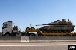 A truck transports an Israeli army main battle tank headed for deployment at the border with Lebanon, along a highway in northern Israel on Sept. 28, 2024.