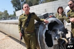 FILE—Israeli military spokesman Rear Admiral Daniel Hagari (L) poses next to an Iranian ballistic missile which fell in Israel, during a media tour at the Julis military base near the southern Israeli city of Kiryat Malachi on April 16, 2024.