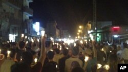 In this citizen journalism image made on a mobile phone Tuesday May 10, 2011 and acquired by the AP, Syrian anti-government protesters carry candles during a rally in the northeastern city of Qamishli, Syria. Syrian activists and eyewitnesses said on Wedn