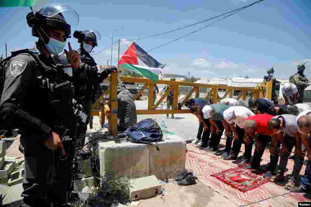 Members of Israeli forces stand guard as Palestinians perform Friday prayers during a protest against Jewish settlements, in Haris near Salfit in the Israeli-occupied West Bank.