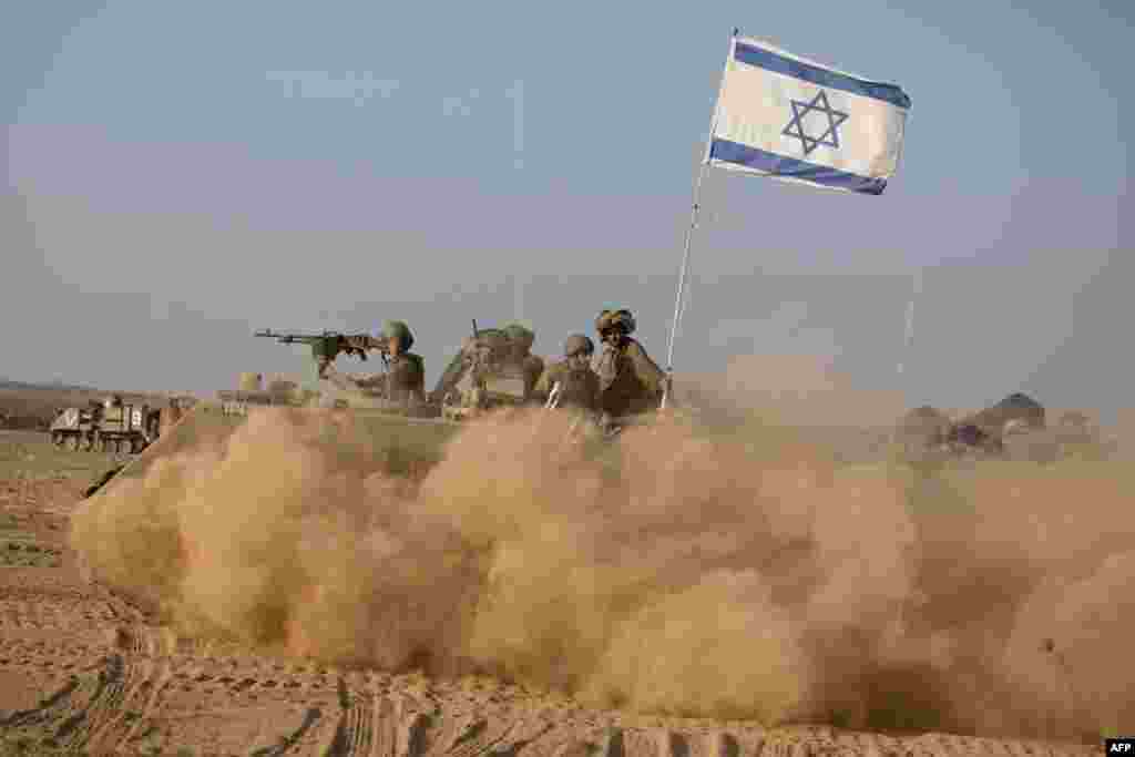 Israeli soldiers fly their flag as they ride an armored personnel carrier in the Gaza Strip, near Israel&#39;s border.
