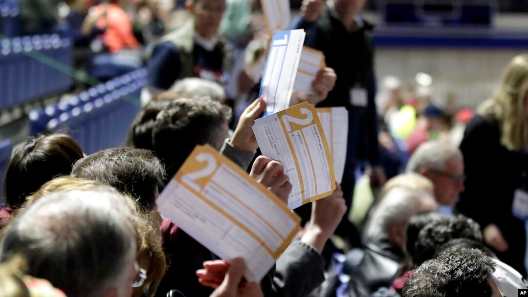 Para peserta Kaukus di bagian tempat duduk untuk kandidat capres dari Demokrat, Joe Biden, mengacungkan surat suara, di Knapp Center, Des Moines, Iowa, 3 Februari 2020.