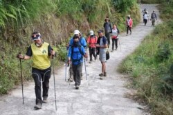 Para pendaki warga negara asing dan Indonesia berjalan di Desa Sembalun setelah turun dari Gunung Rinjani di Lombok Timur, 30 Juli 2018. (Foto: Akbar Nugroho Gumay/Antara Foto via Reuters)