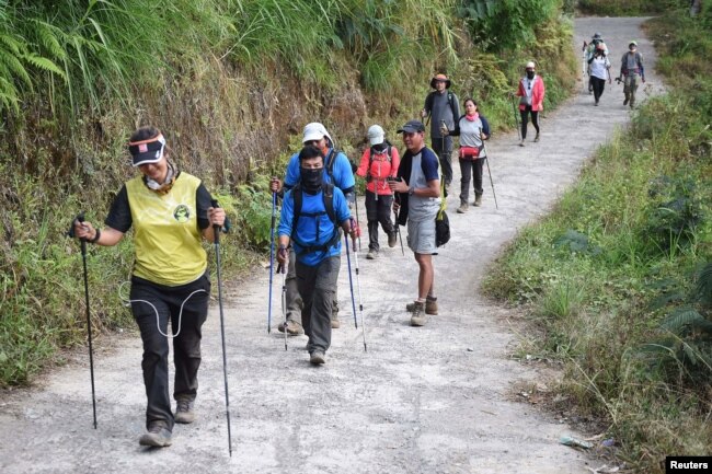 Para pendaki warga negara asing dan Indonesia berjalan di Desa Sembalun setelah turun dari Gunung Rinjani di Lombok Timur, 30 Juli 2018. (Foto: Akbar Nugroho Gumay/Antara Foto via Reuters)