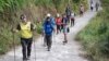 Para pendaki warga negara asing dan Indonesia berjalan di Desa Sembalun setelah turun dari Gunung Rinjani di Lombok Timur, 30 Juli 2018. (Foto: Akbar Nugroho Gumay/Antara Foto via Reuters)