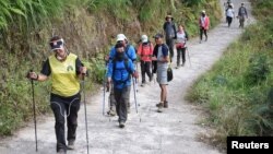 Para pendaki warga negara asing dan Indonesia berjalan di Desa Sembalun setelah turun dari Gunung Rinjani di Lombok Timur, 30 Juli 2018. (Foto: Akbar Nugroho Gumay/Antara Foto via Reuters)