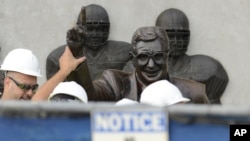 Trabajadores remueven la estatua del legendario entrenador de fútbol colegial universitario, Joe Patterno, el domingo, en el estadio de Penn State.