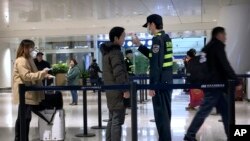 중국 우한 톈허 국제공항에서 공항 관계자가 21일 적외선 온도계를 사용해 공항 이용객의 발열을 확인하고 있다. 