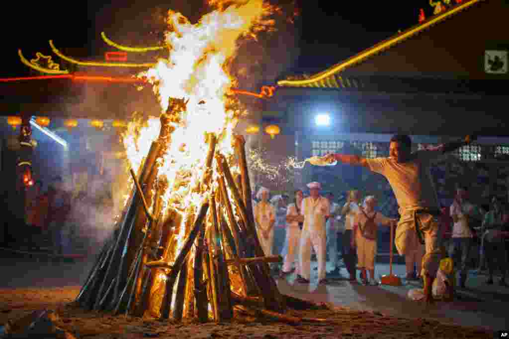 A man sets wood on fire to prepare for worshipers to walk barefoot over burning coals during the Nine Emperor Gods festival at a temple in Kuala Lumpur, Malaysia.